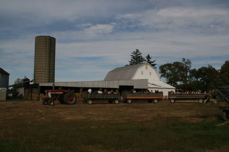 Tractor and open passenger wagons beside the barn at Circle S Farms