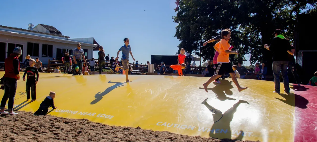 Visitors on a yellow jumping pillow at Deal’s Orchard