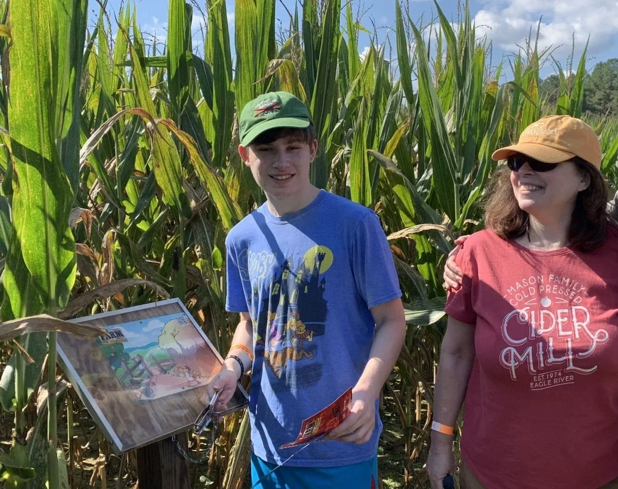 Two visitors with a maze map beside the corn at Gross Farms