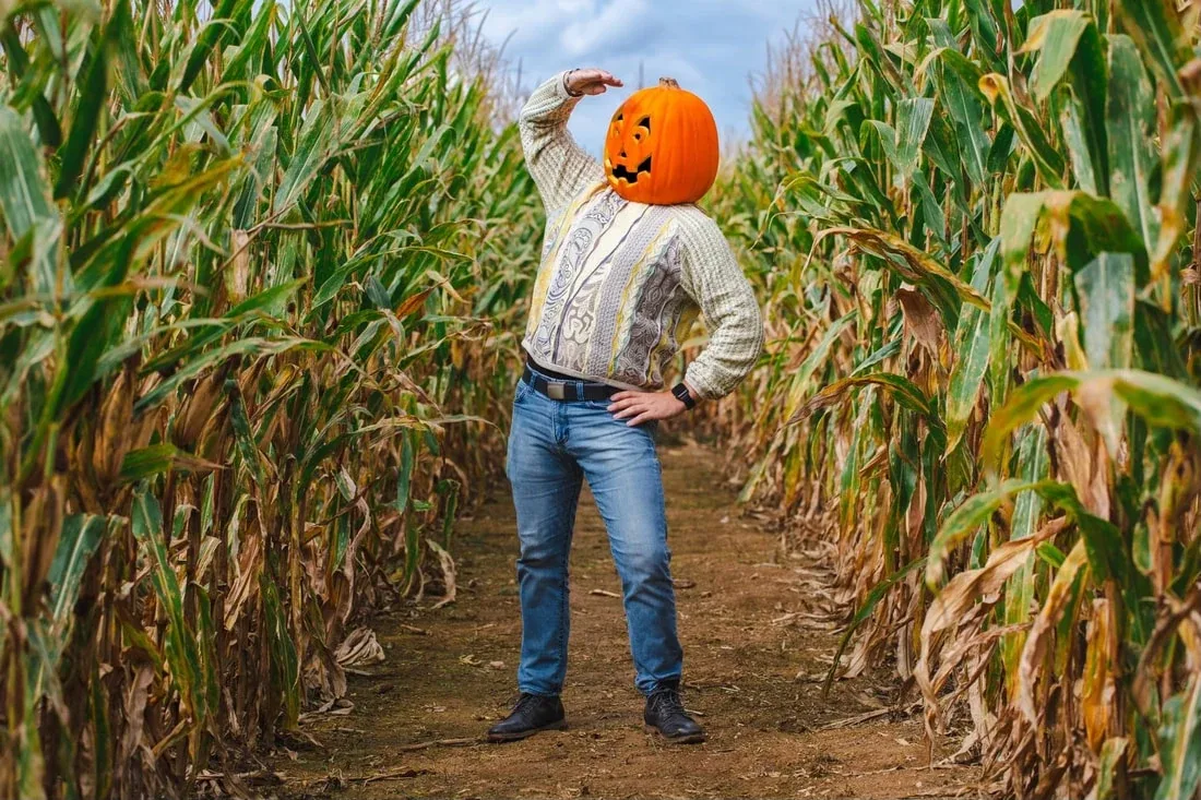 A visitor wearing a pumpkin mask in Kidd Family Farm’s corn maze