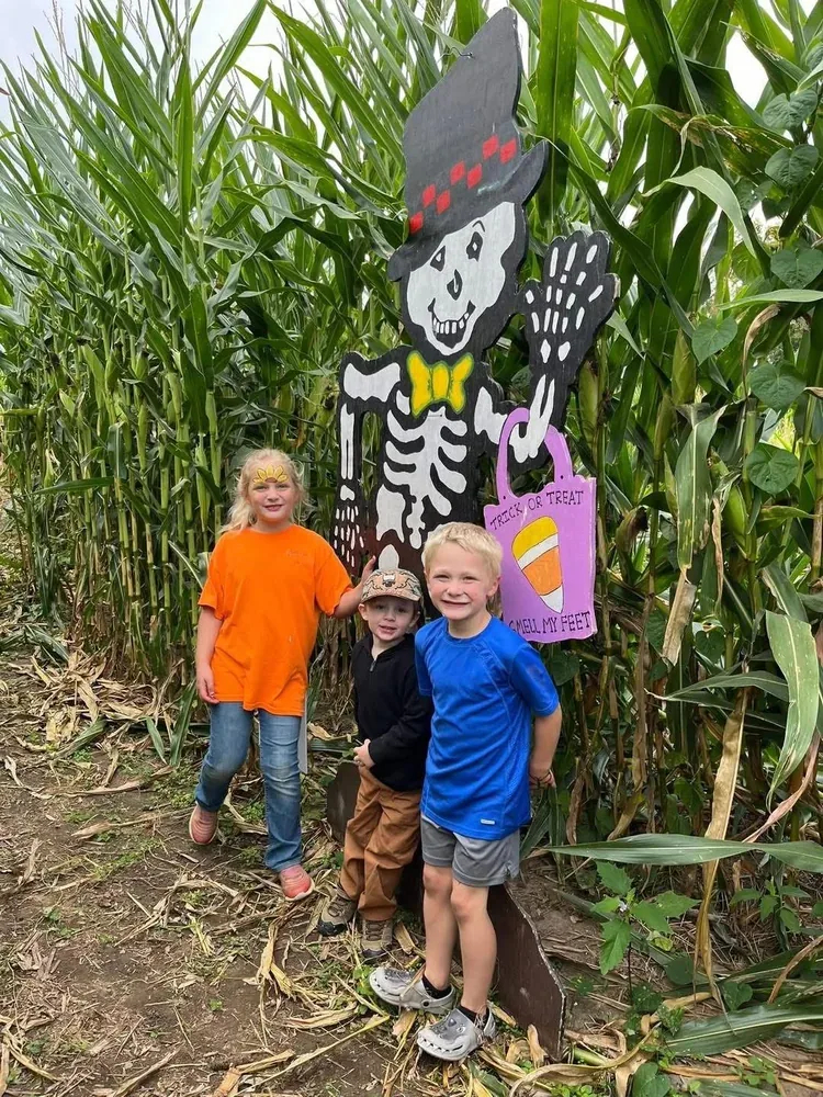 Children beside a skeleton sign among corn rows at Lohstroh Family Farms